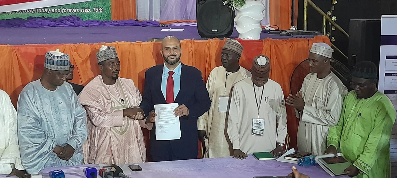 Participants display a document and shake hands at a partnership signing.